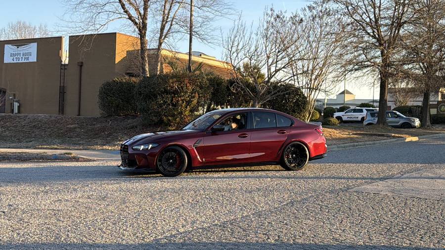 Maroon 2026 BMW M3 Competition parked in front of a brick building